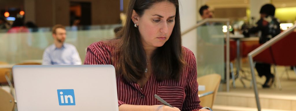 employee sitting at table with computer, and writing down professional career highlights
