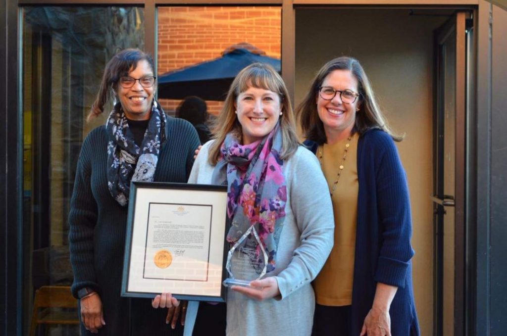 Lara D. with two friends. Lara is holding the Pennsylvania Governor's Victim Service Pathfinder Award.