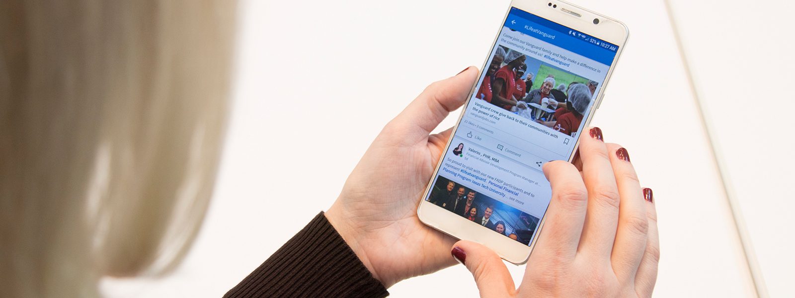 closeup on phone in hands of employee. The phone screen shows the employee's social media feed.