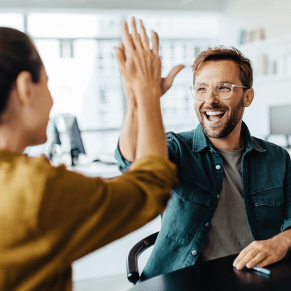 Man and woman giving each other a high-five and smiling.