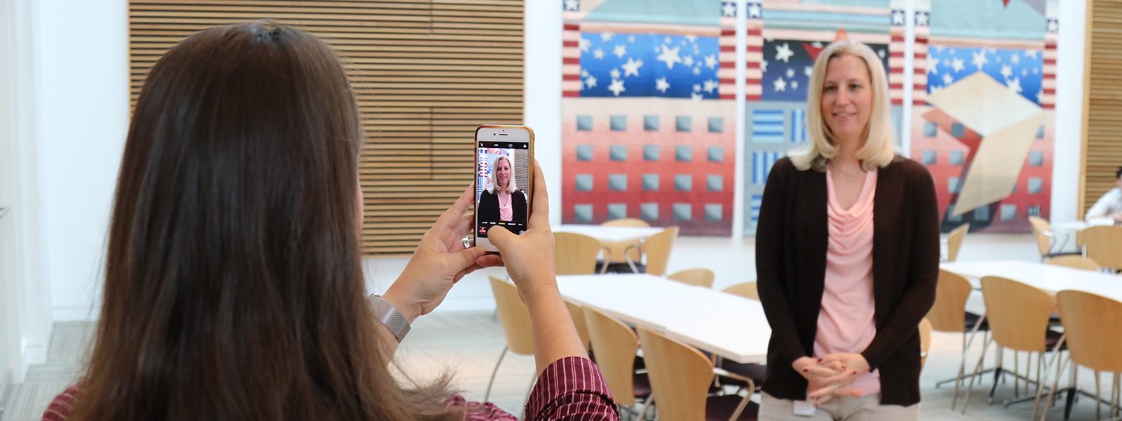 employee with phone taking a professional headshot of another employee