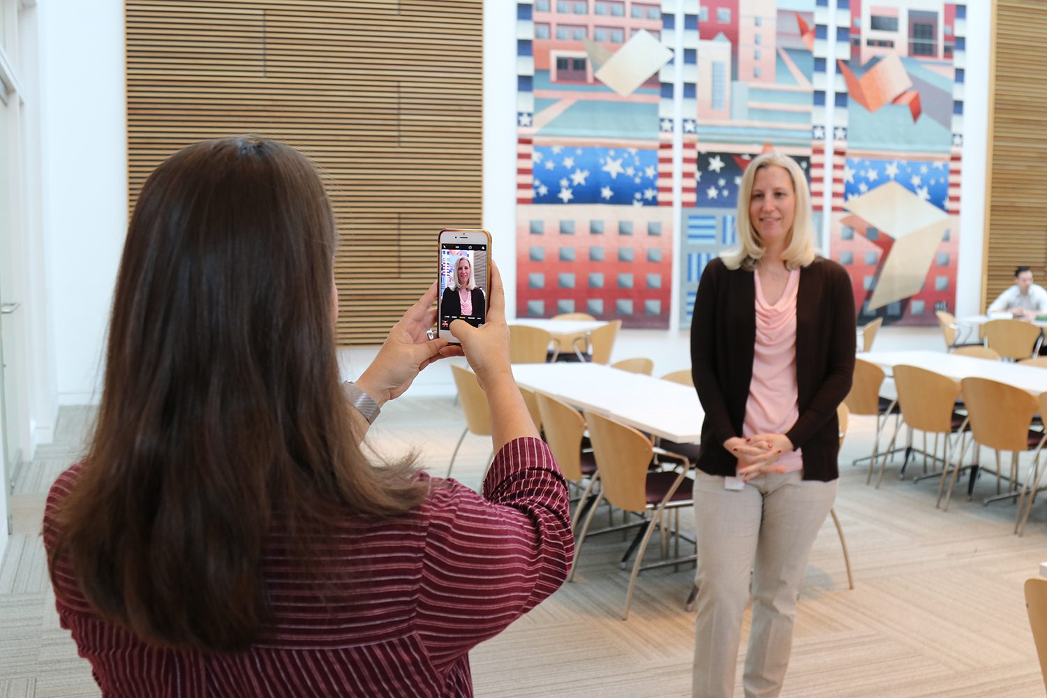 employee with phone taking a professional headshot of another employee