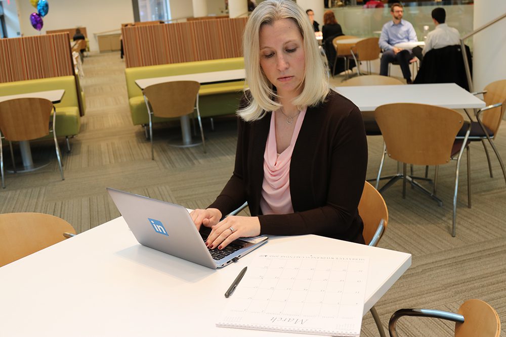 employee reviewing content ideas at table and typing them on a computer