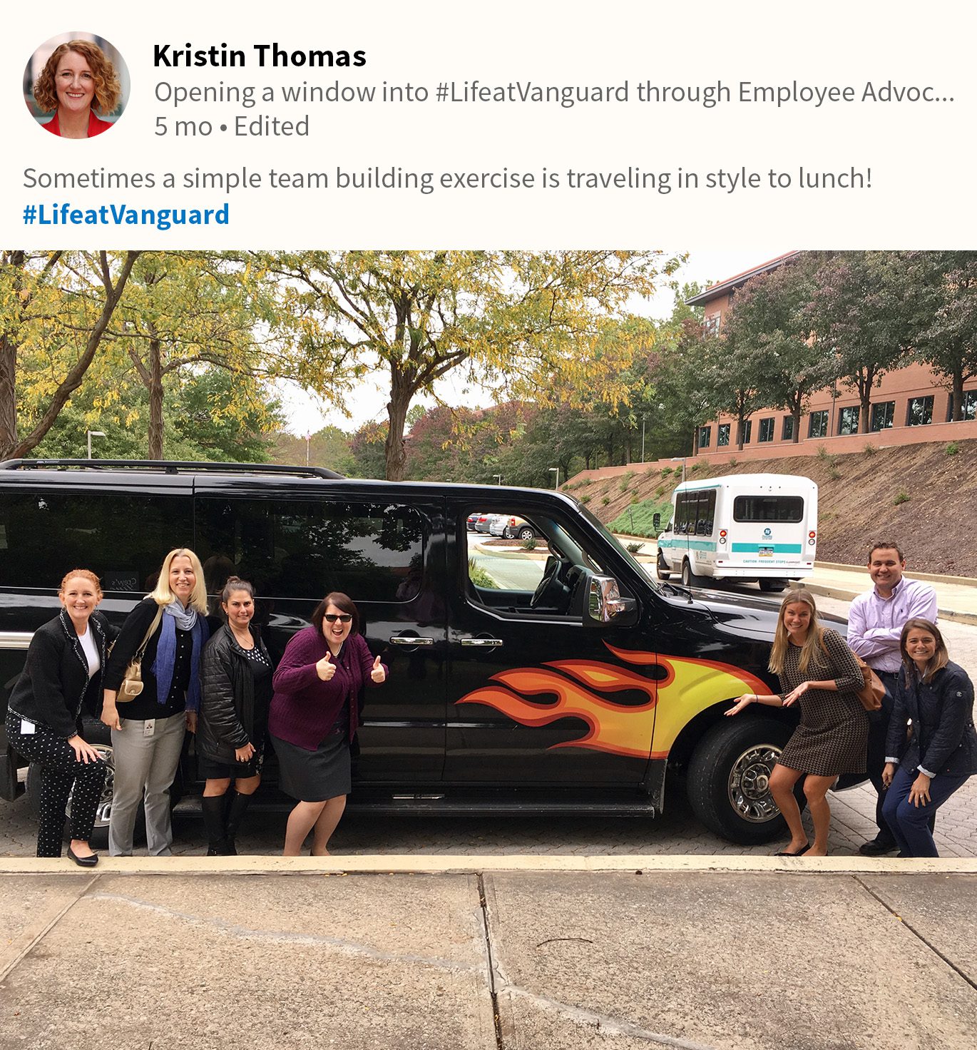 screenshot of social post with seven employees posing in front of a mini van with a fire design on the side and headed to a team lunch.