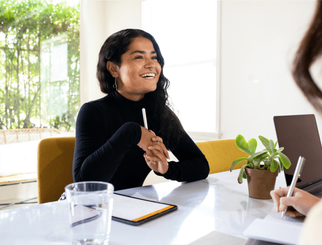 A female student laughing while seated across from her mentor.