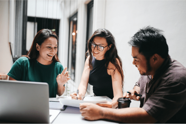 Group of diverse coworkers sitting together at a table and reviewing a document.