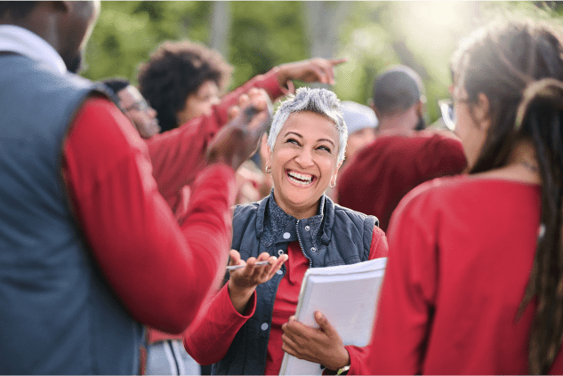 Woman holding a checklist and laughing while she volunteers with coworkers.