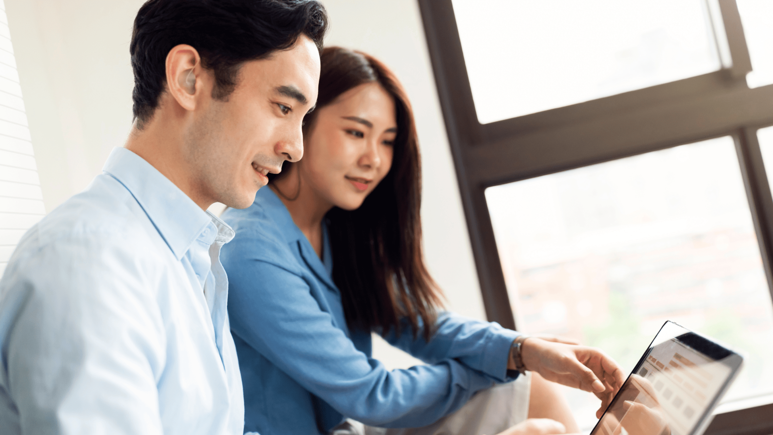 Man and woman sitting and looking at a laptop screen together.