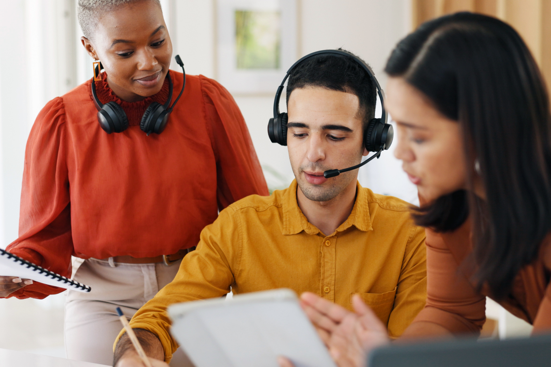 Three coworkers in a call center. The women on the left and right are mentoring the man in the middle.