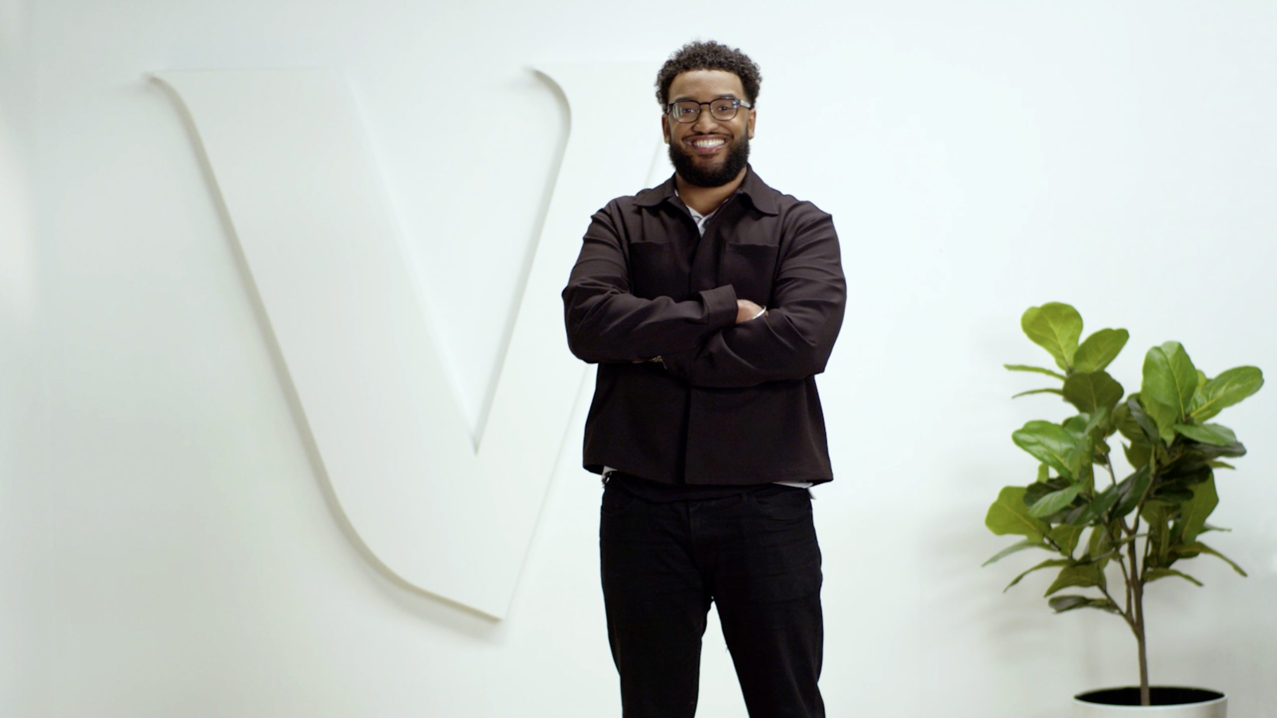 : Quentin M. standing with arms crossed in front of a white wall