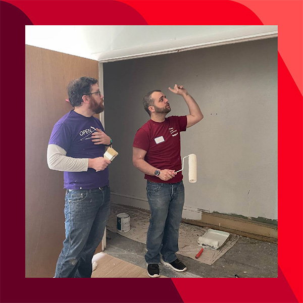 Vanguard_Social_WebContent_Josh_U_A_600x600 Josh U-A and another person stand in a room being painted, holding a paintbrush and roller, with supplies on the floor and partially painted walls behind them.